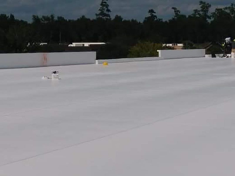 A man is standing on top of a white roof.