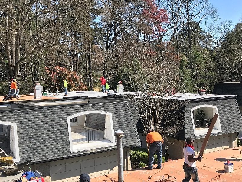 A group of men are working on the roof of a house.