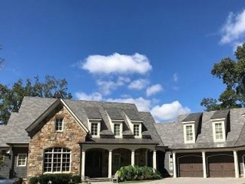 A large house with a car parked in front of it on a sunny day.