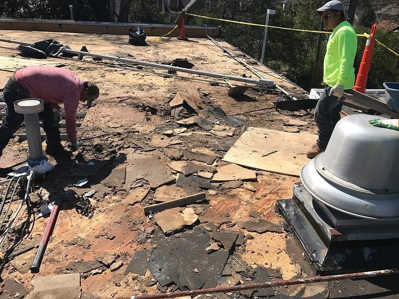 Two men are working on the roof of a building.