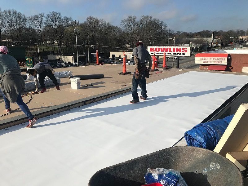 A group of people are working on a roof in front of a bowling alley.
