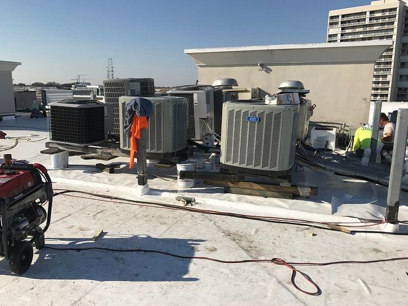 A generator is sitting on the roof of a building next to a bunch of air conditioners.