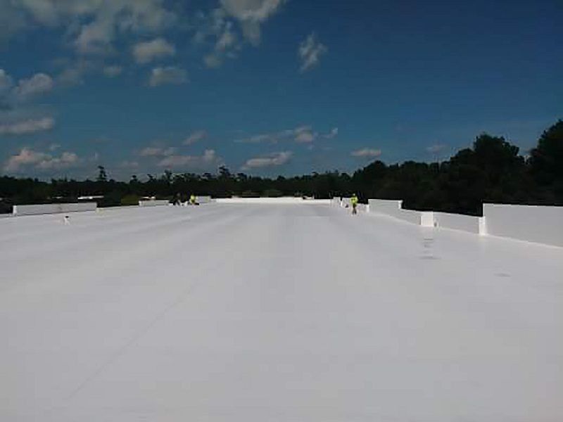 A white roof with a blue sky and trees in the background.