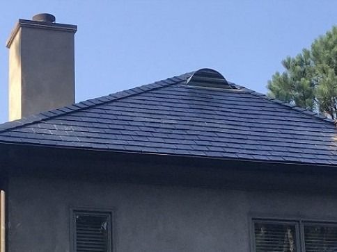A house with a slate roof and a chimney on top of it.