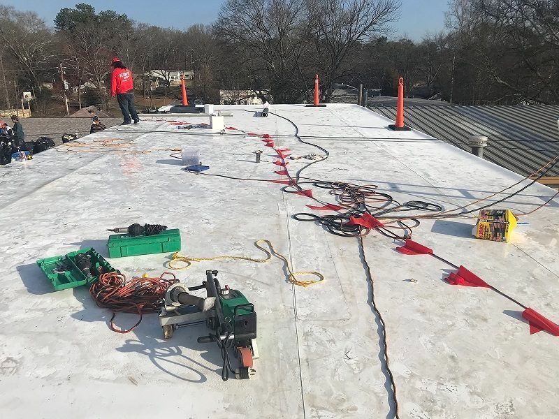 A man is standing on top of a white roof.