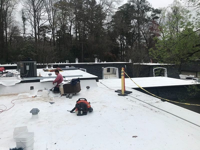 A man is standing on top of a white roof.