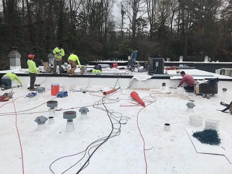 A group of people are working on a white roof.