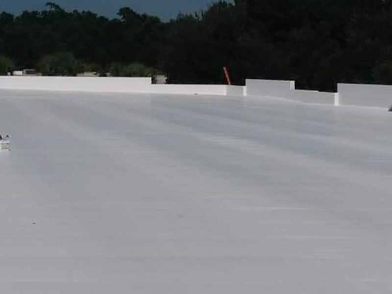 A large white roof with trees in the background.