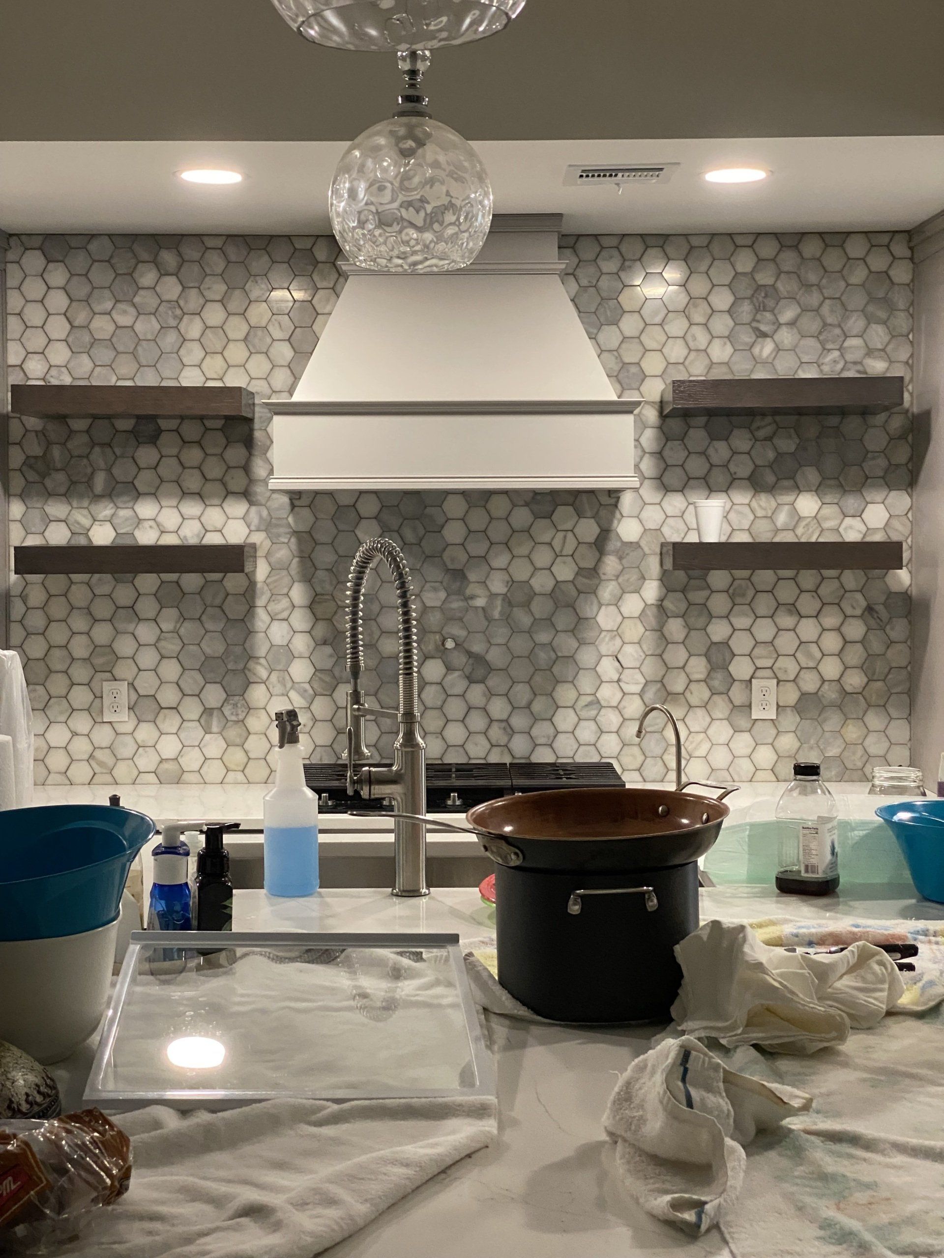 A kitchen with a sink , stove , pots and pans on the counter.