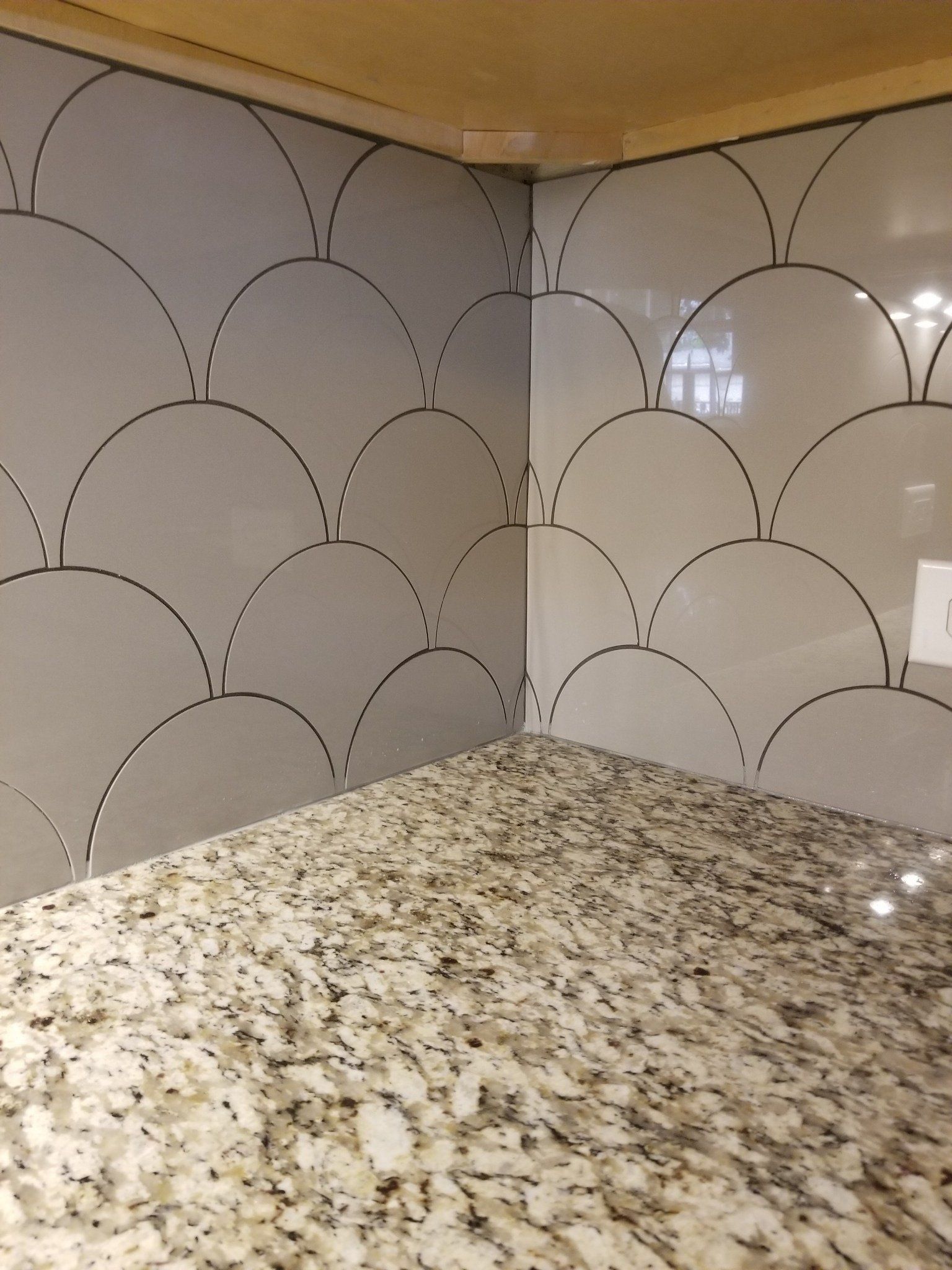 A granite counter top with a gray tile wall behind it.