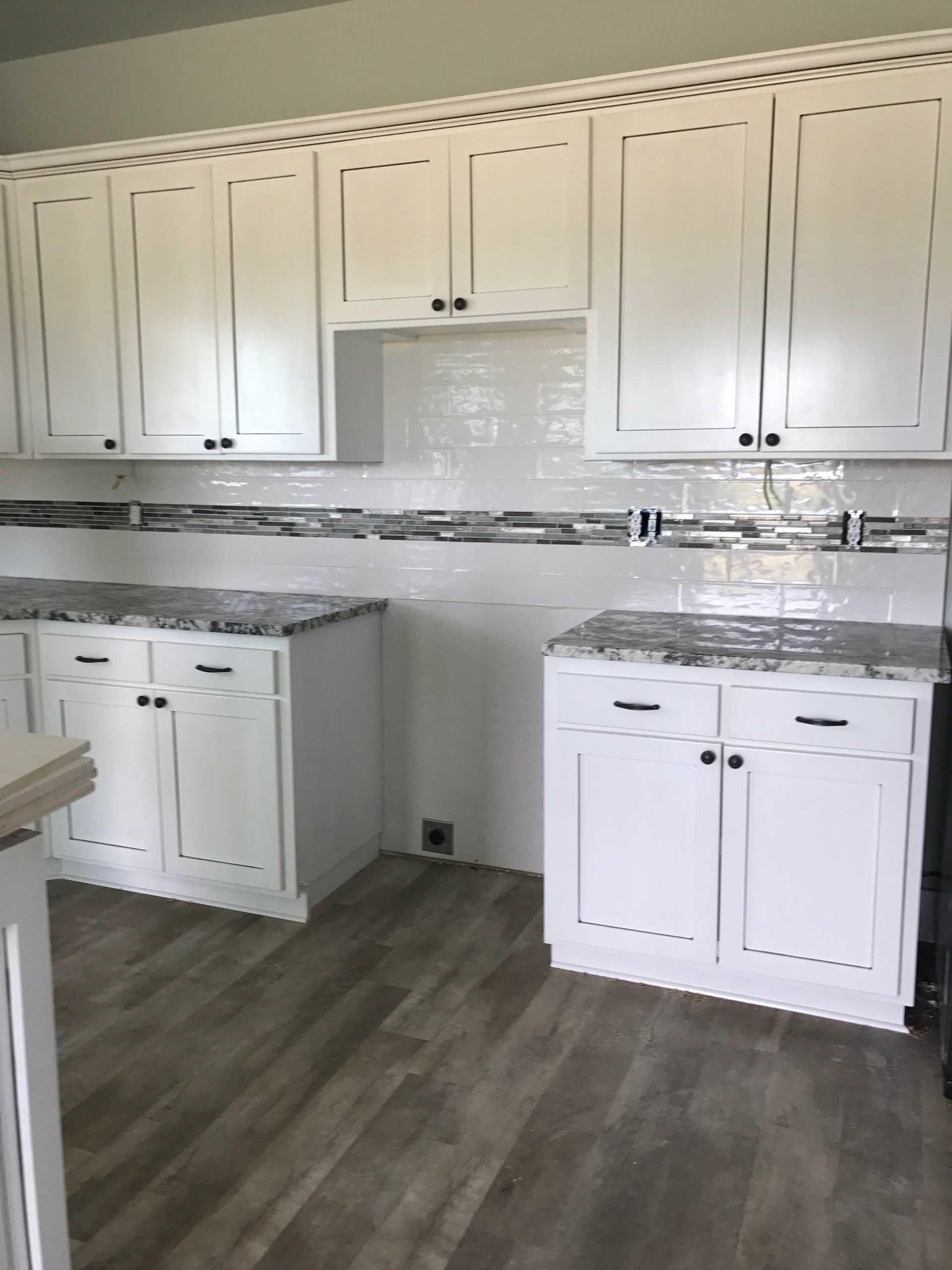 A kitchen with white cabinets and marble counter tops