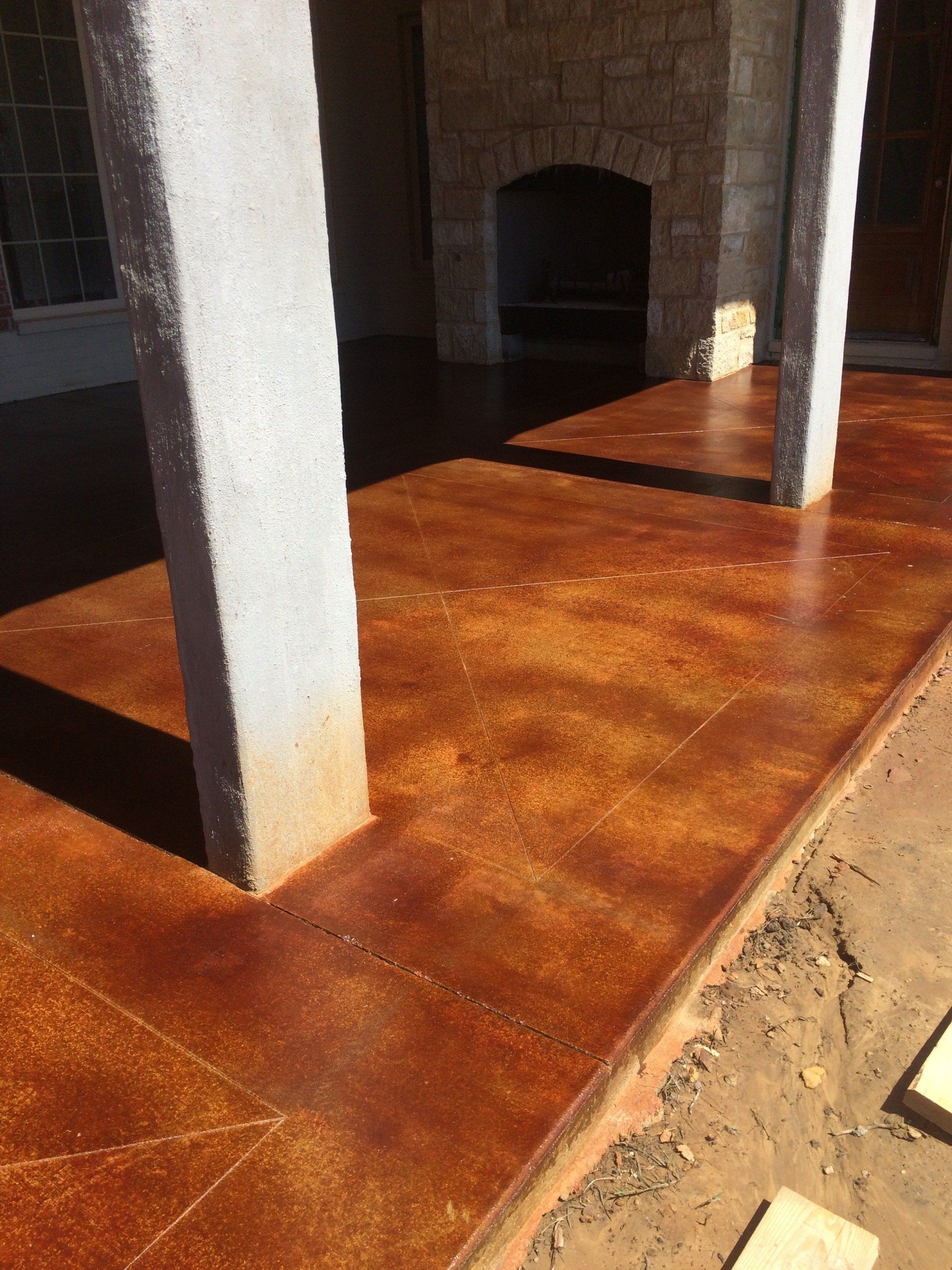 A patio with a stained concrete floor and pillars.
