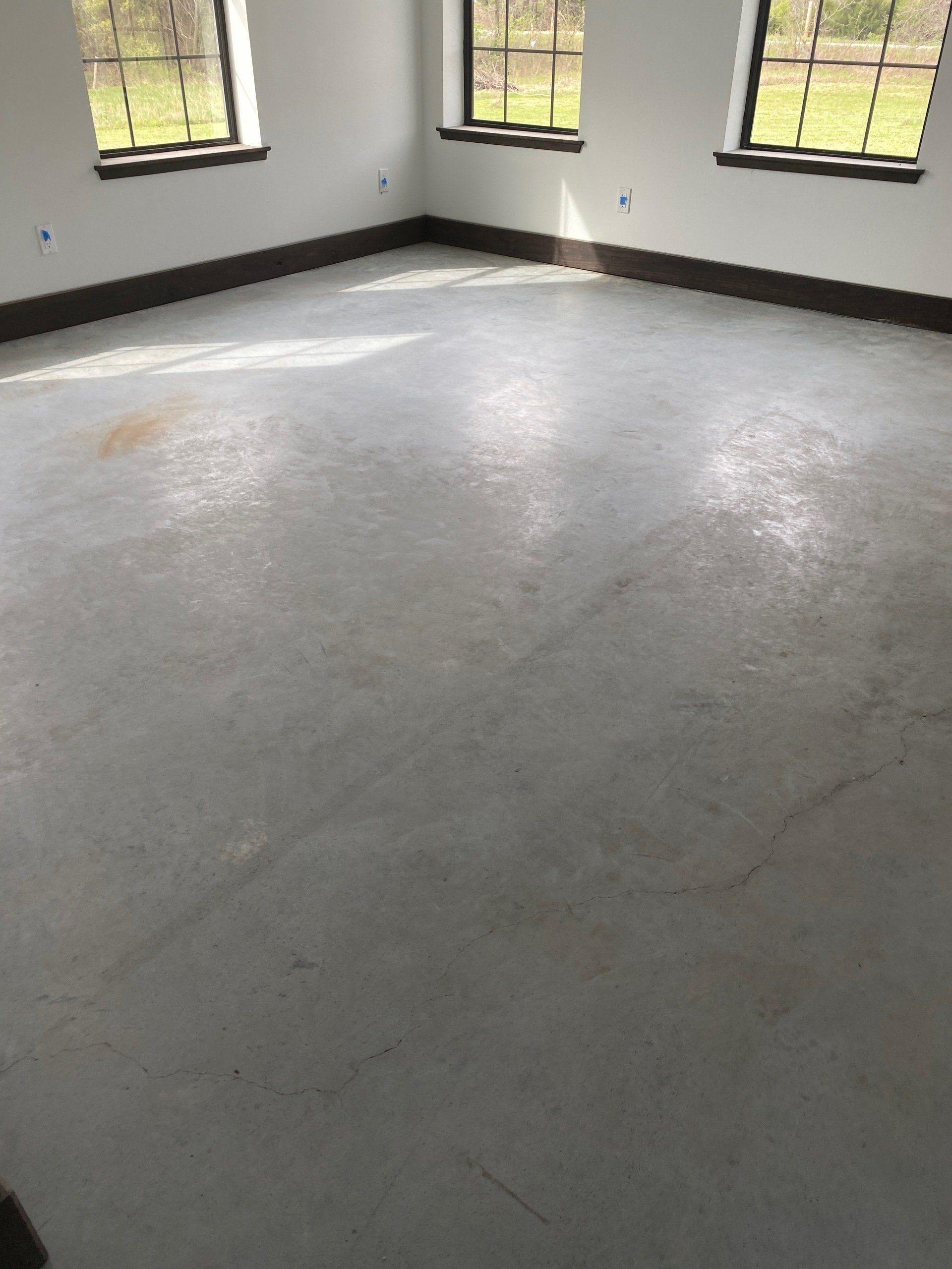 An empty room with a concrete floor and windows