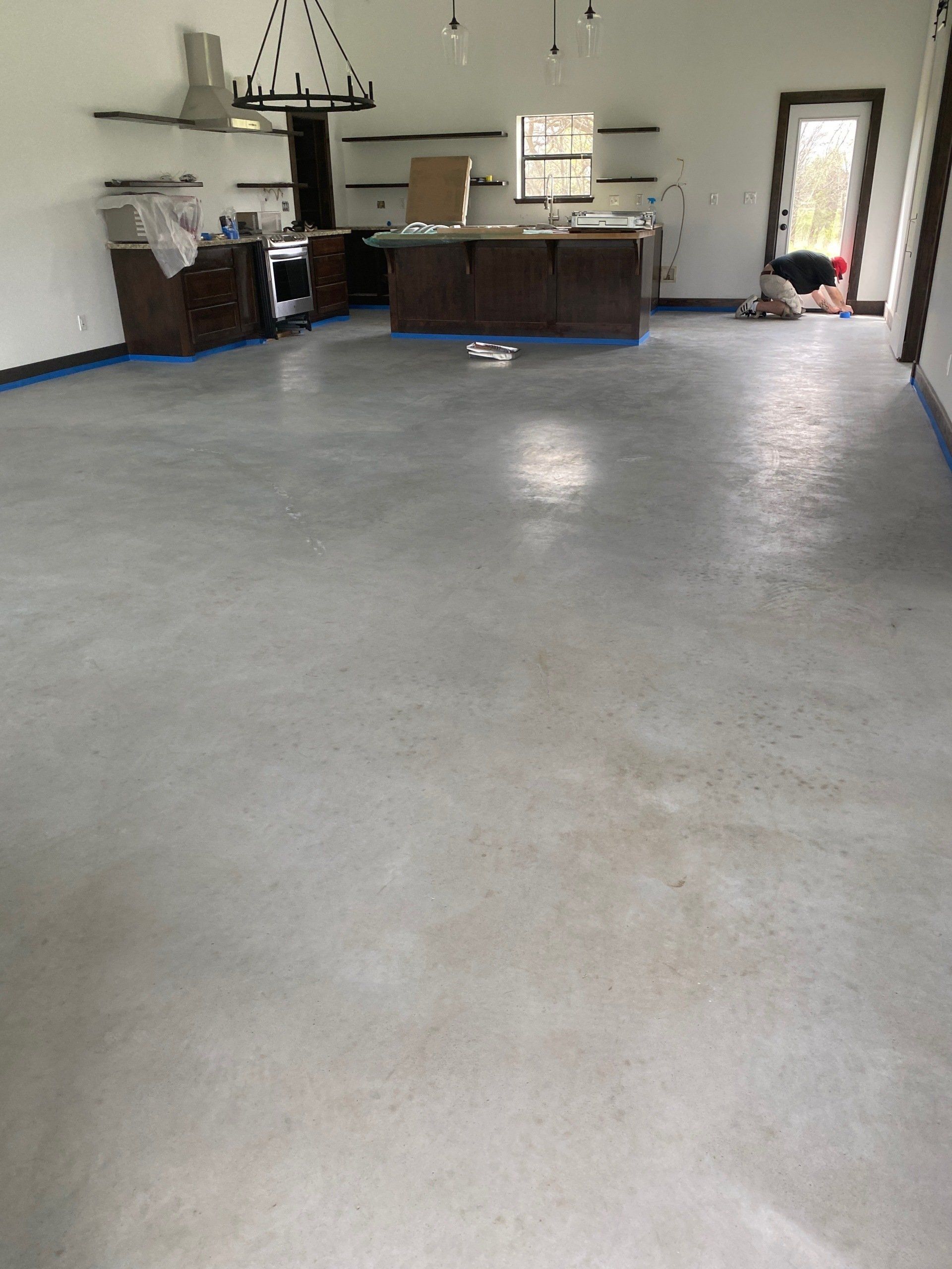 A kitchen with a concrete floor and a chandelier hanging from the ceiling.