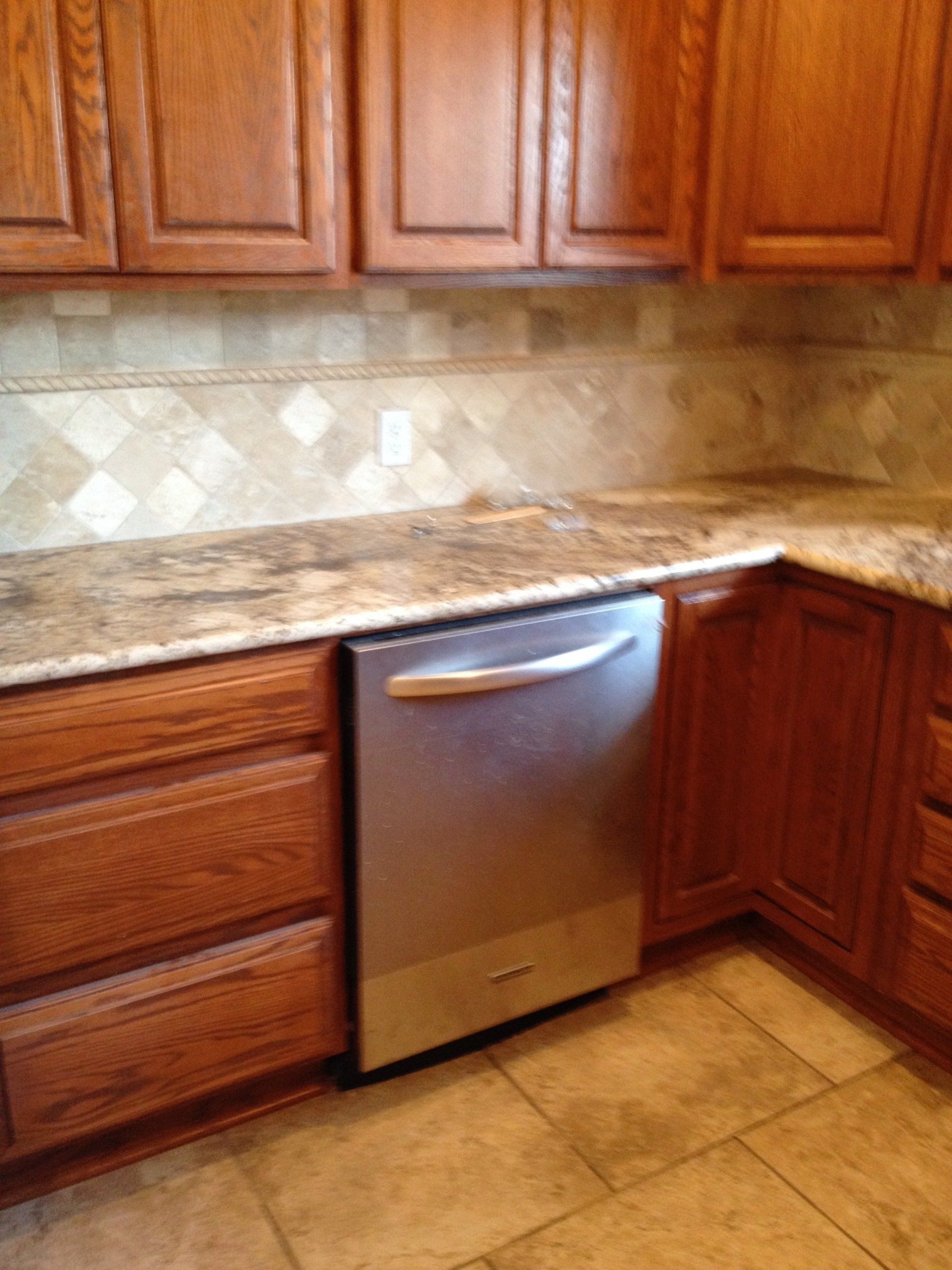 A kitchen with wooden cabinets and a stainless steel dishwasher