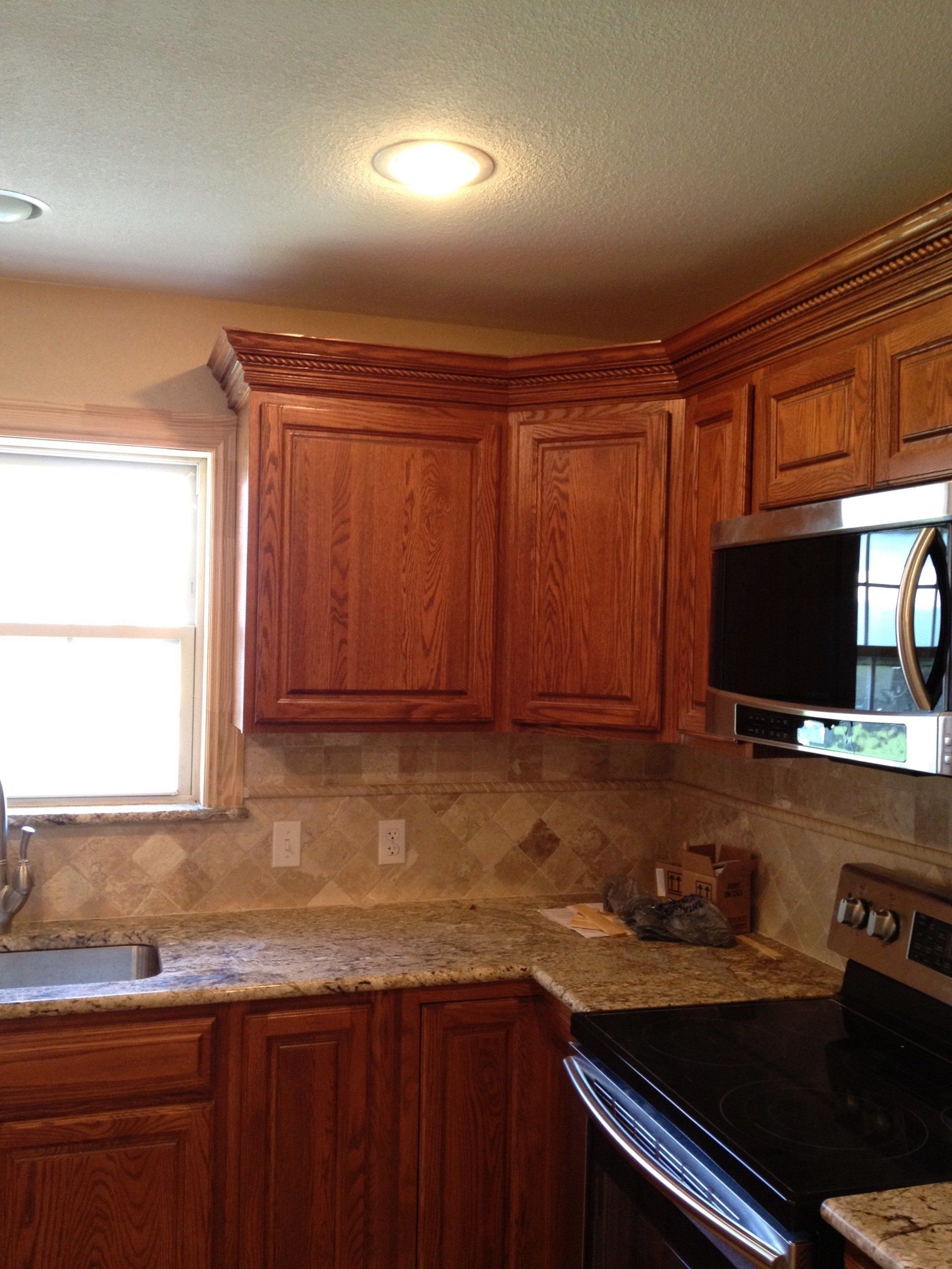 A kitchen with wooden cabinets , granite counter tops , stainless steel appliances and a window.