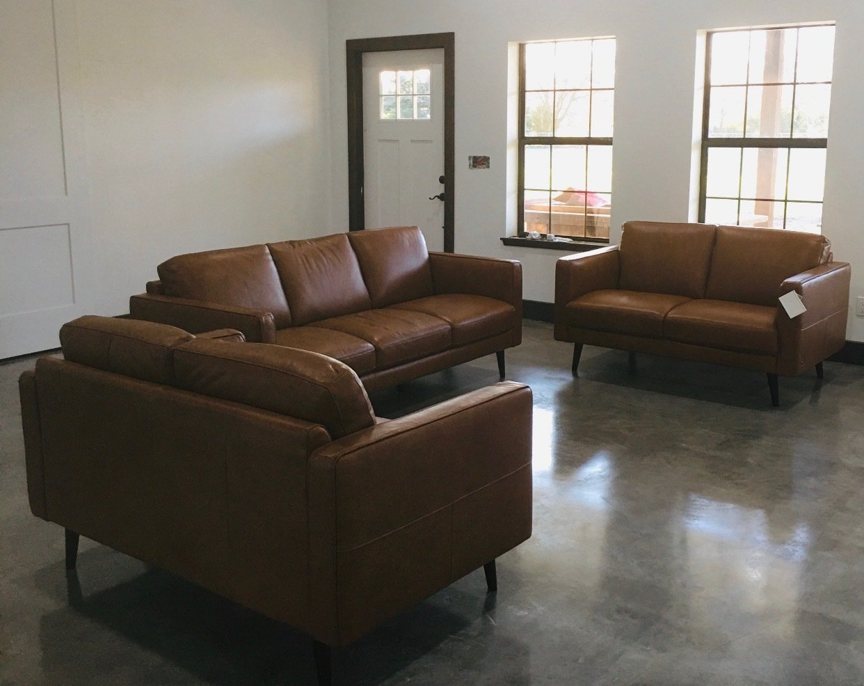 A living room with two brown leather couches and a chair