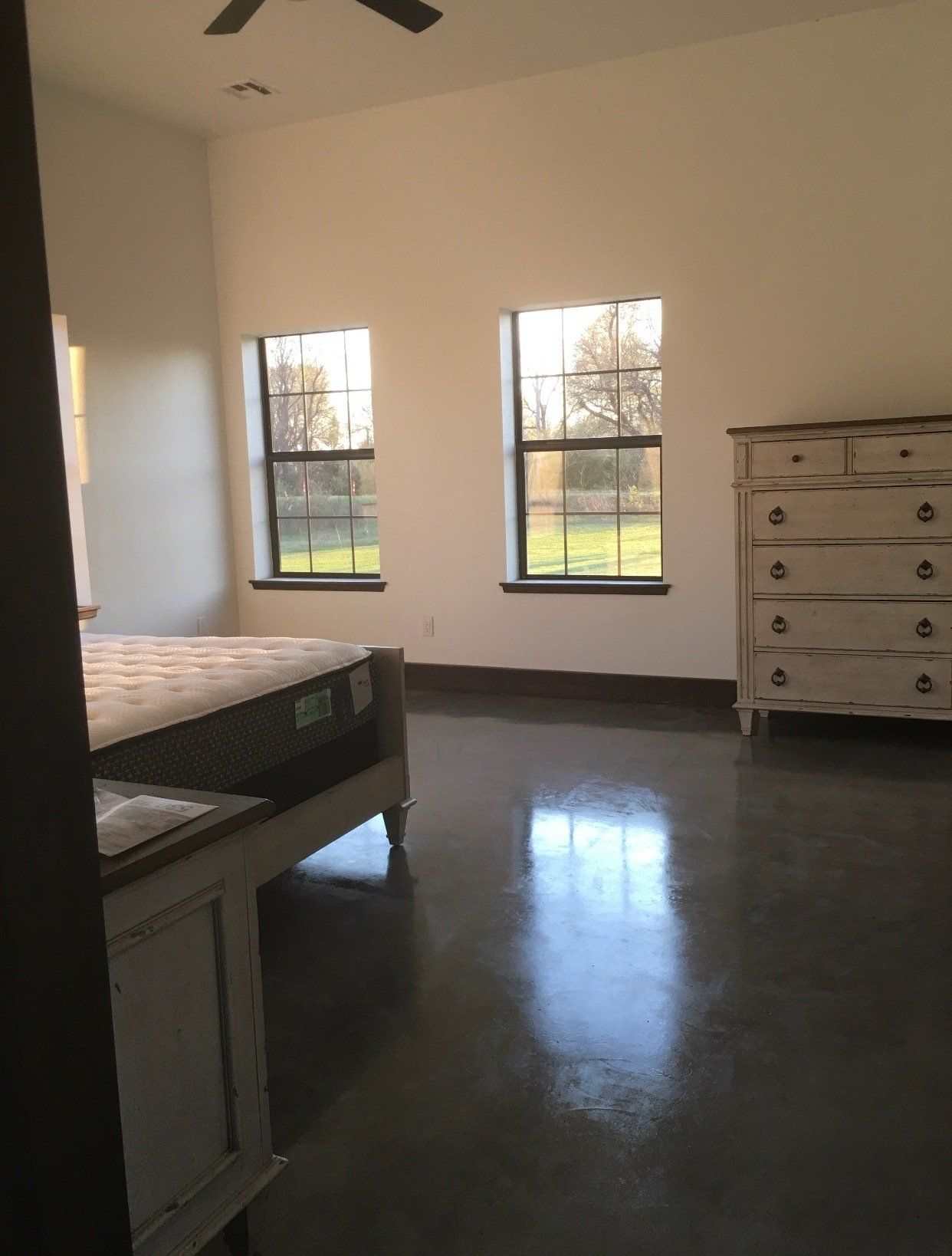 A bedroom with a bed , dresser and two windows