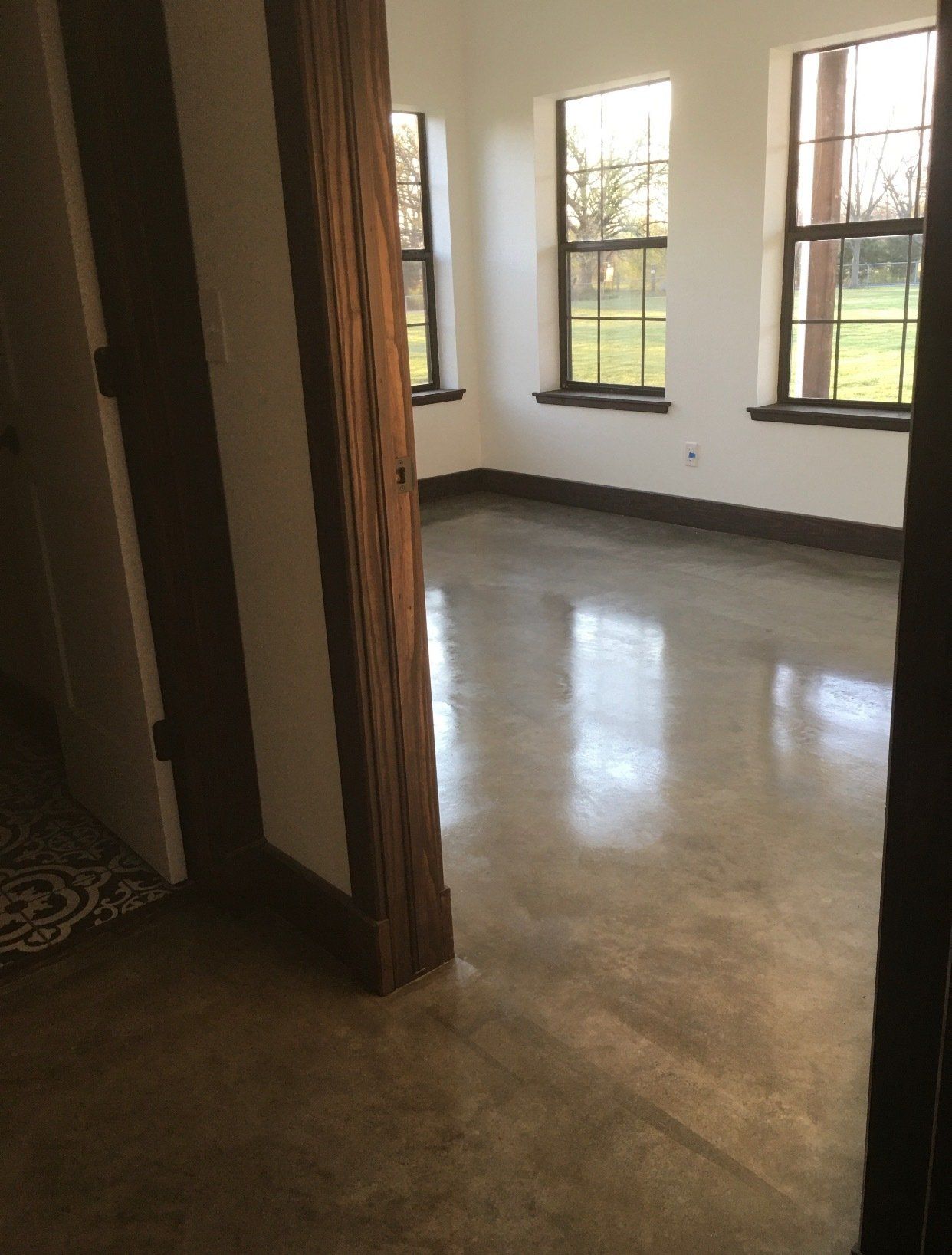 An empty room with a concrete floor and two windows