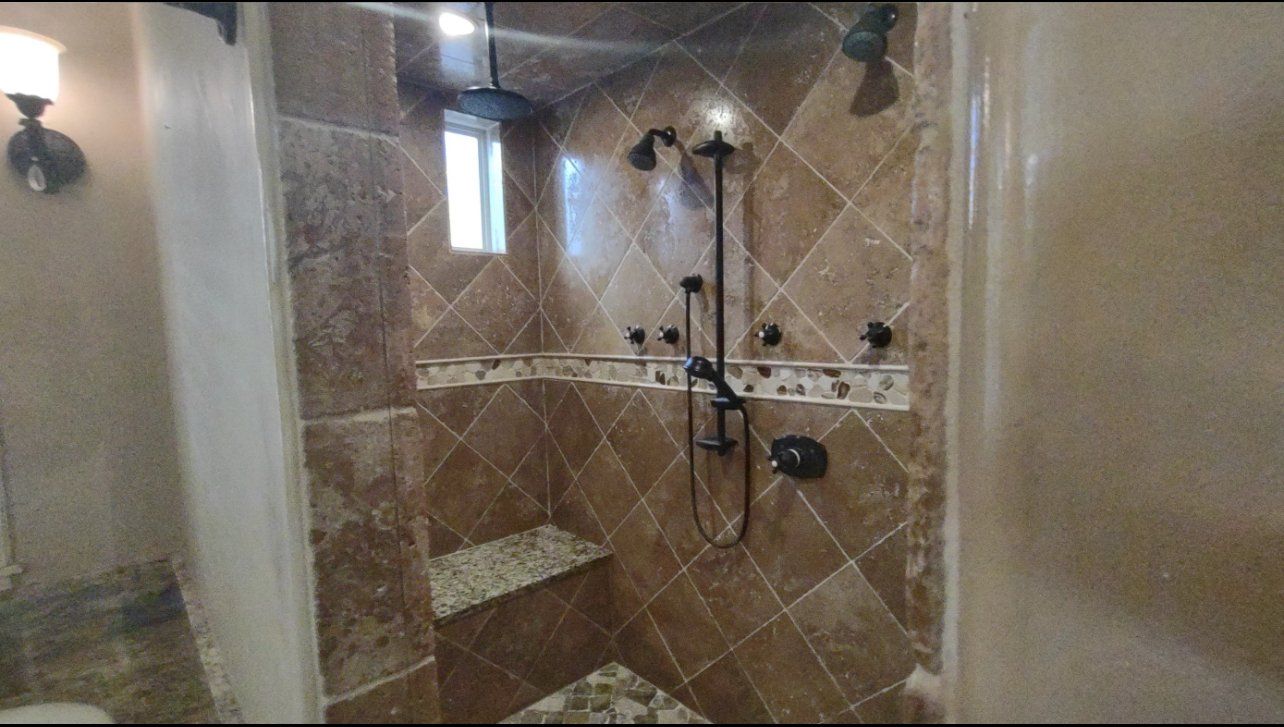 A bathroom with a walk in shower and a sink.
