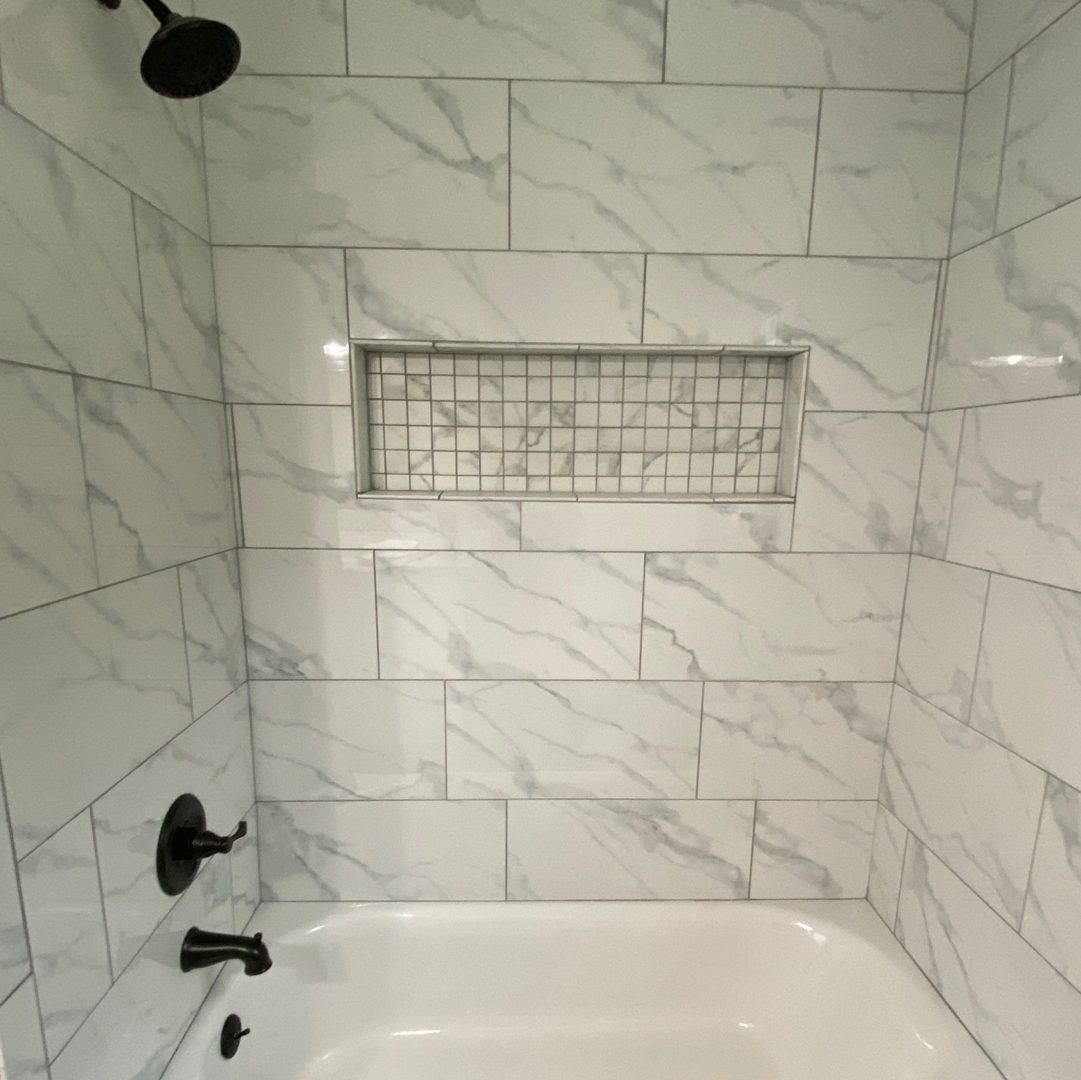 A bathroom with white tiles and a bathtub and shower.
