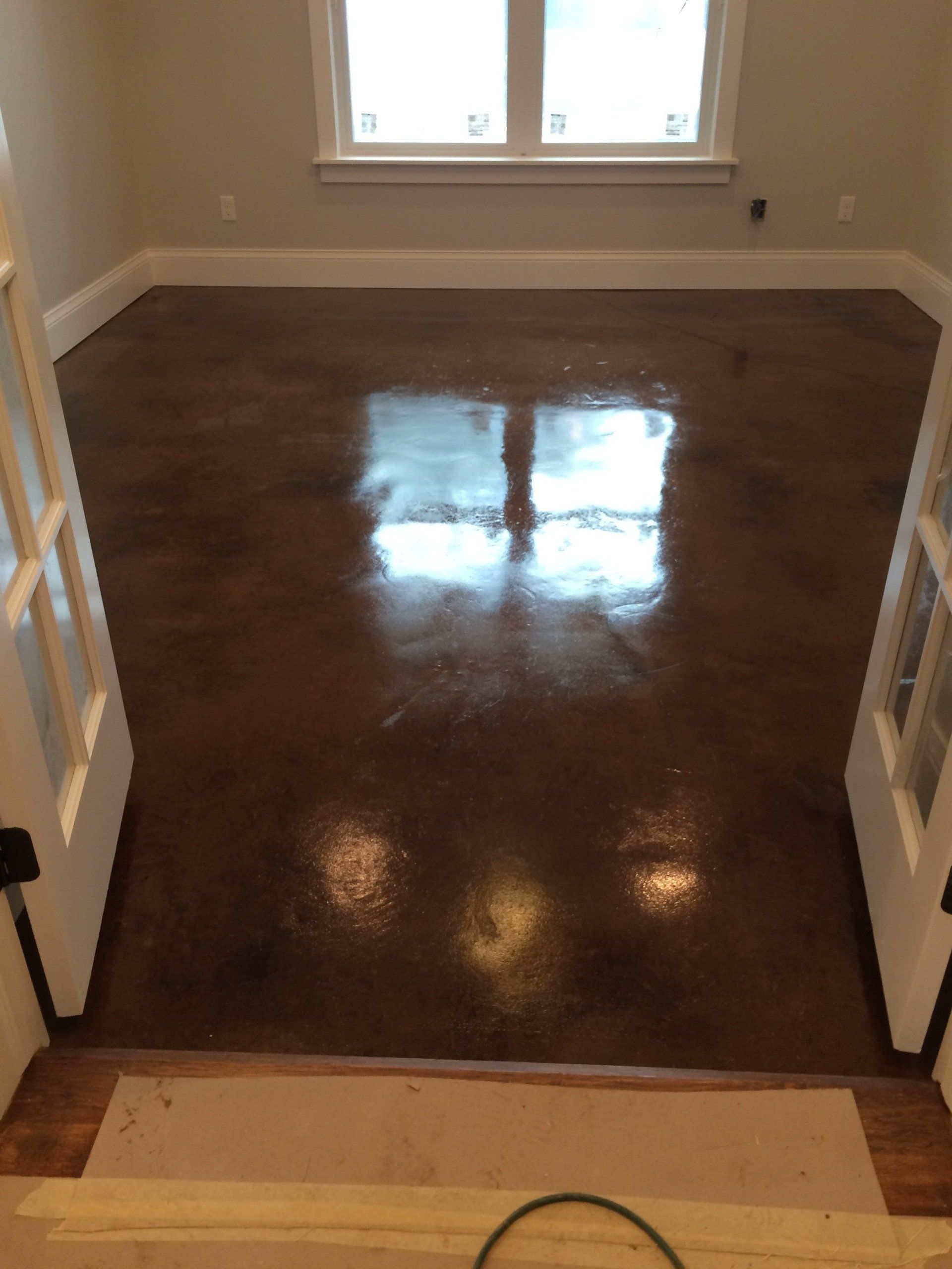 A living room with a shiny concrete floor and a window.