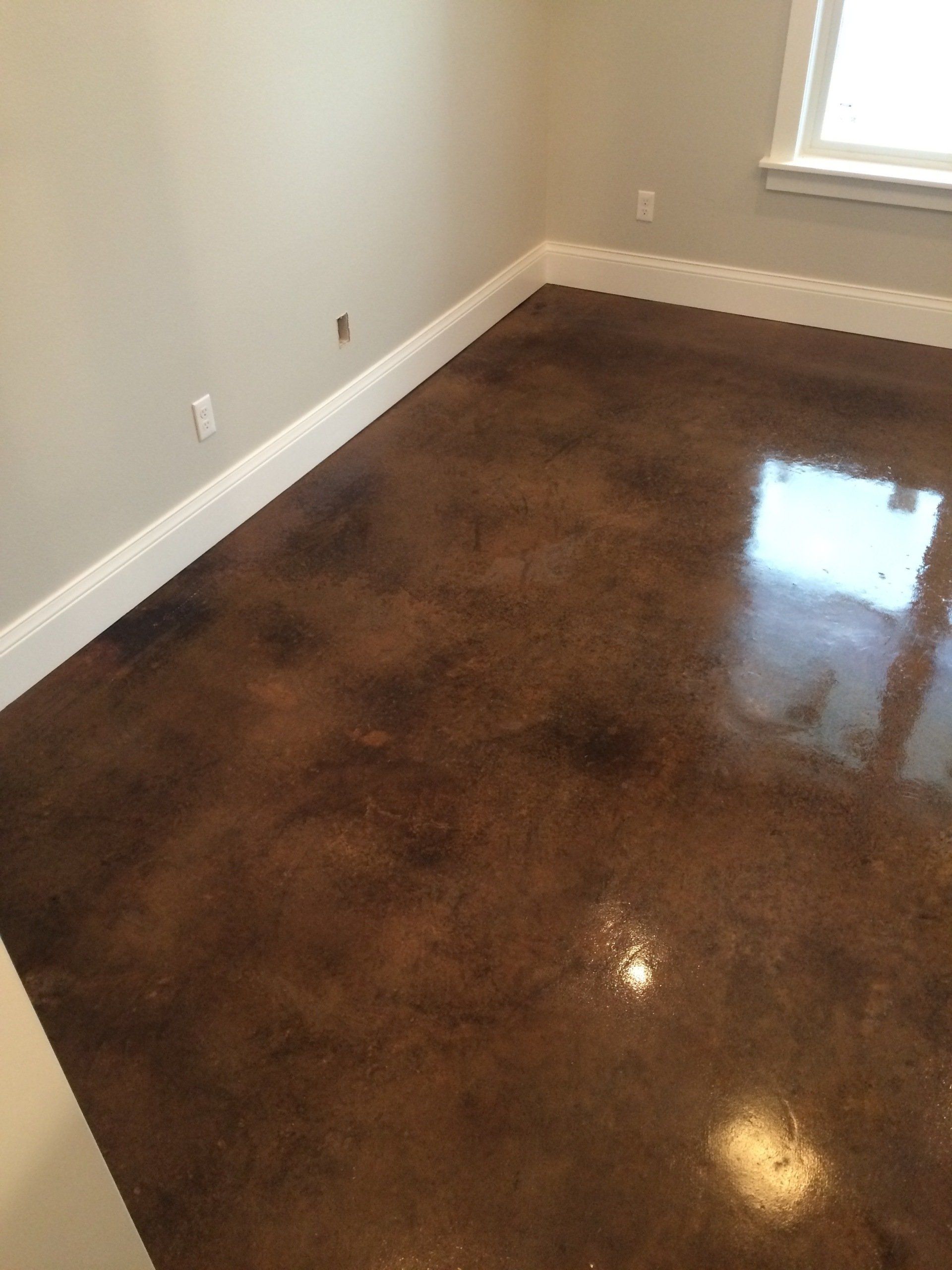 A room with a brown concrete floor and white trim.