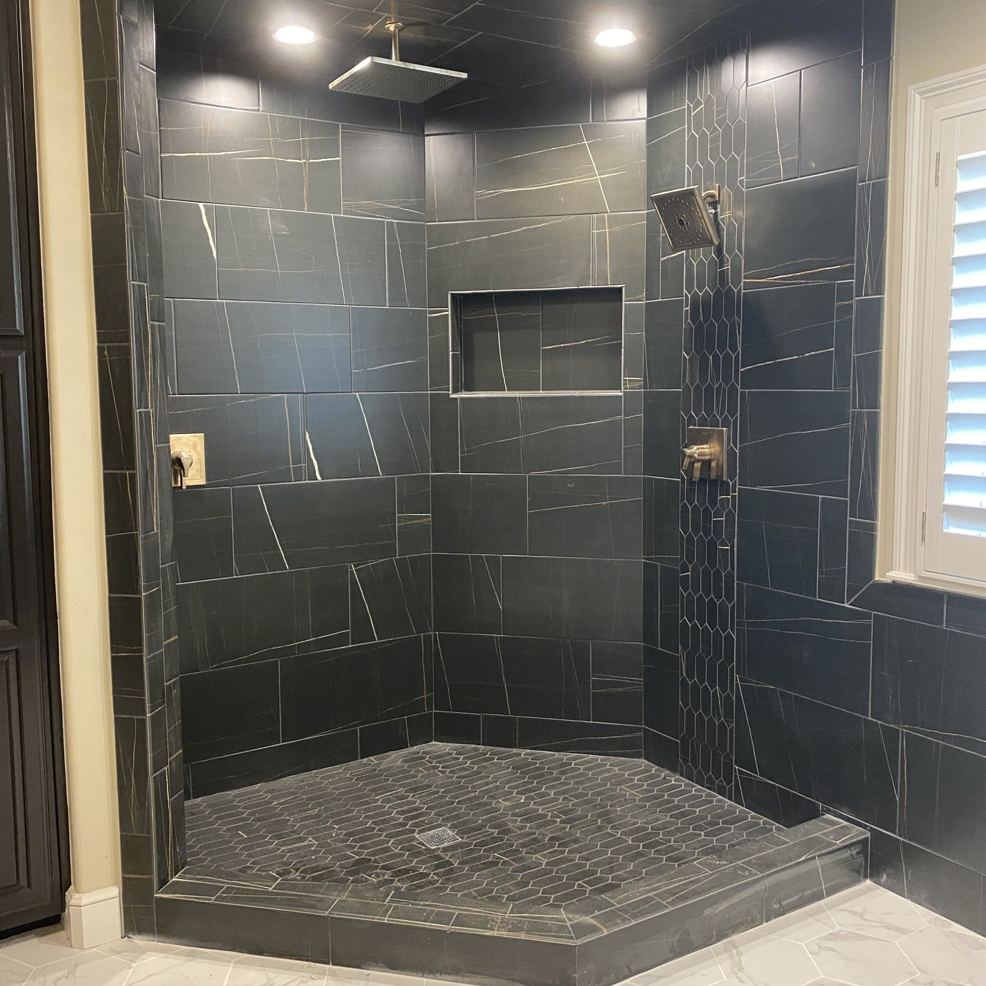 Awesome black tiles, shower installed, shampoo box/shelf, wainscot tile