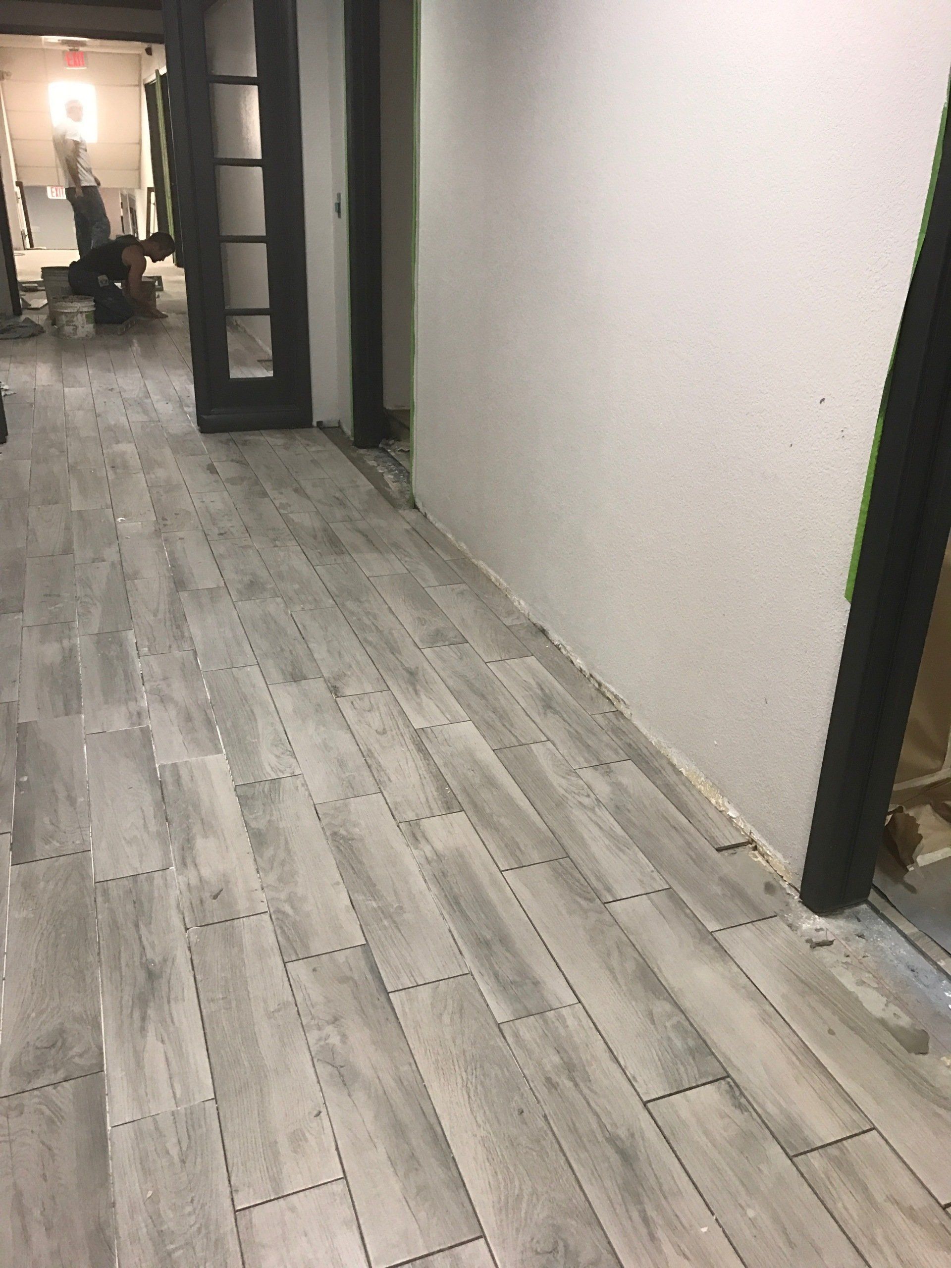 A hallway with a wooden floor and a white wall.
