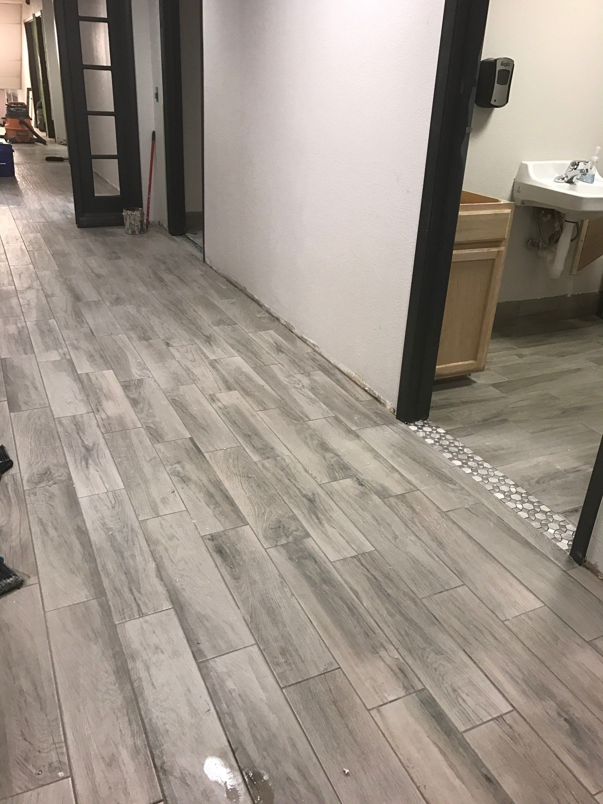 A hallway with a wooden floor and a sink.