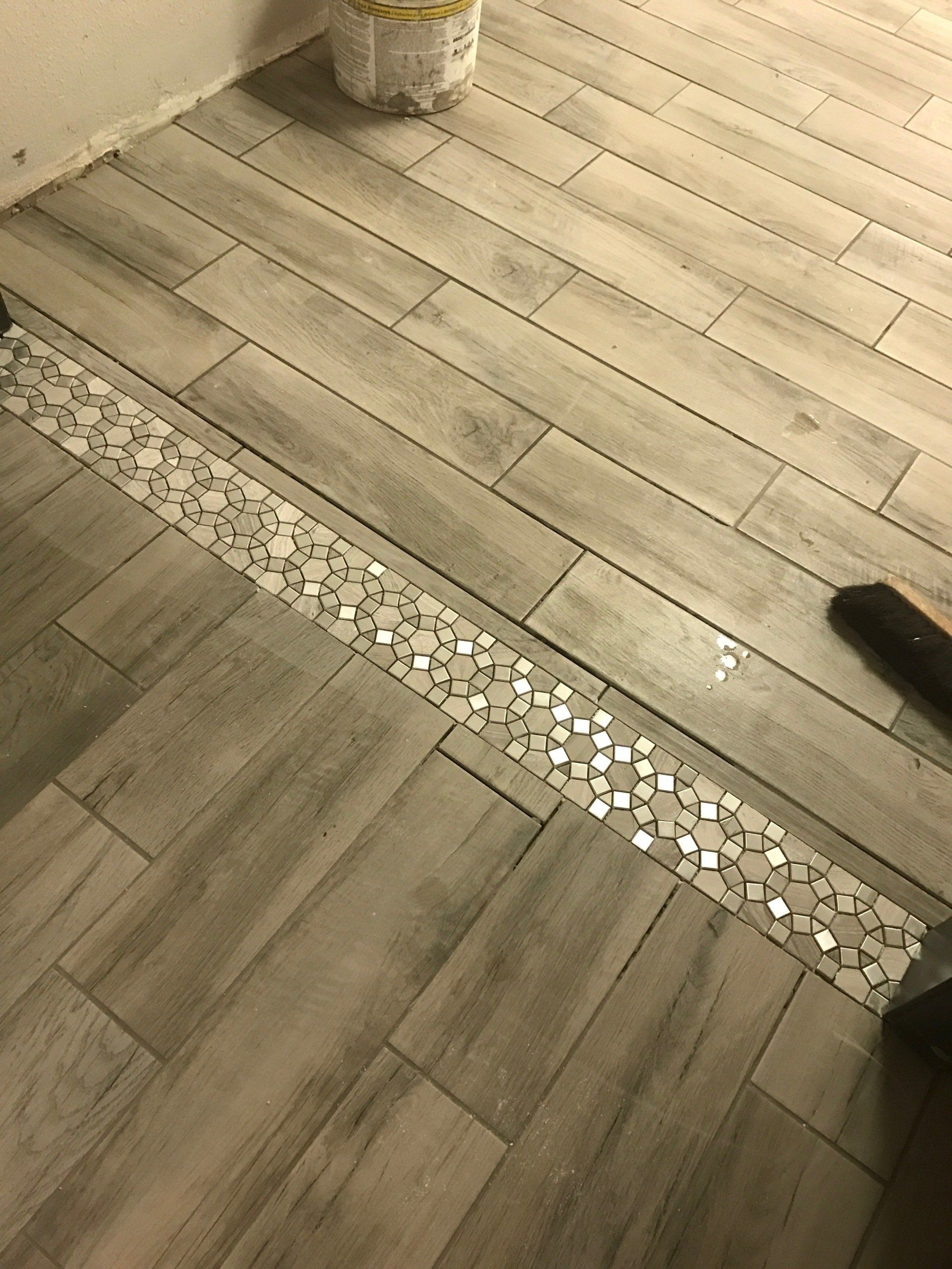 A close up of a wooden floor with a mosaic border.