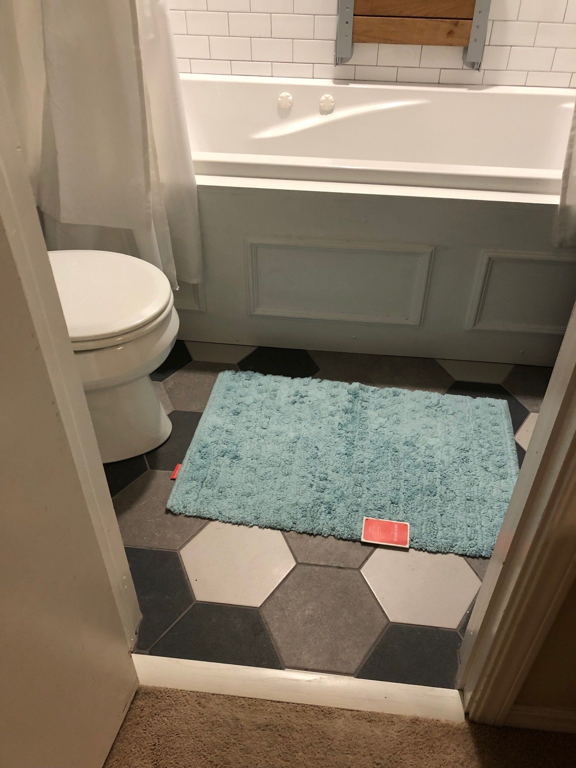 A bathroom with a toilet , bathtub , and rug on the floor.