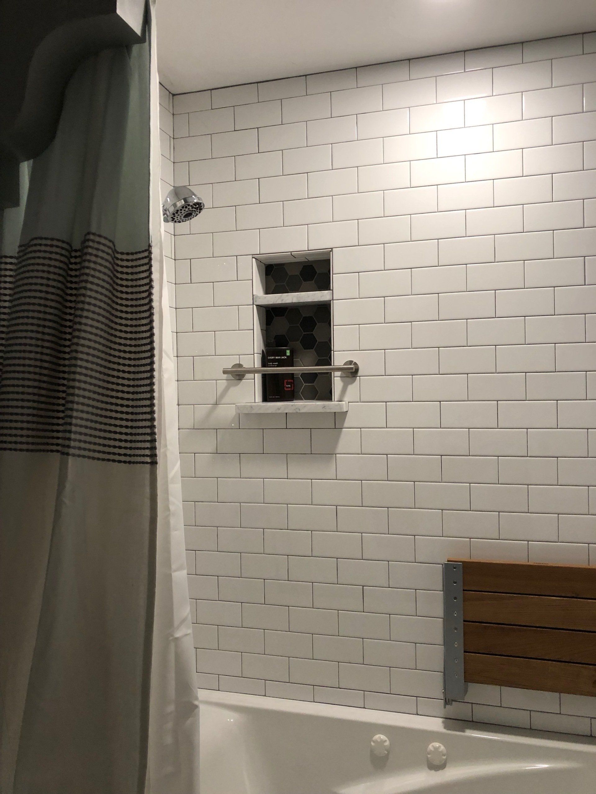 A bathroom with a tub , shower , and brick wall.