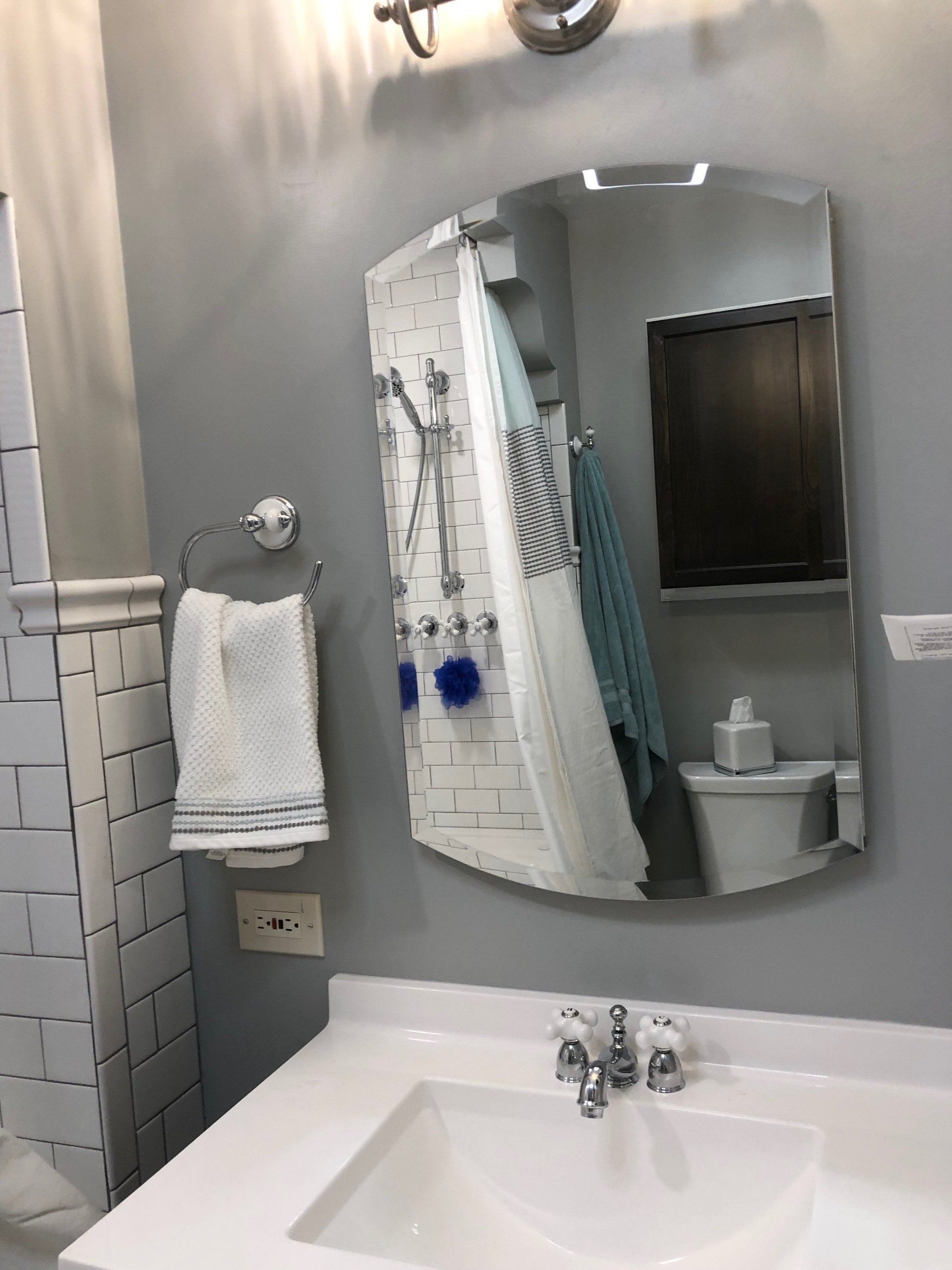 A bathroom with a sink , toilet , shower and mirror.