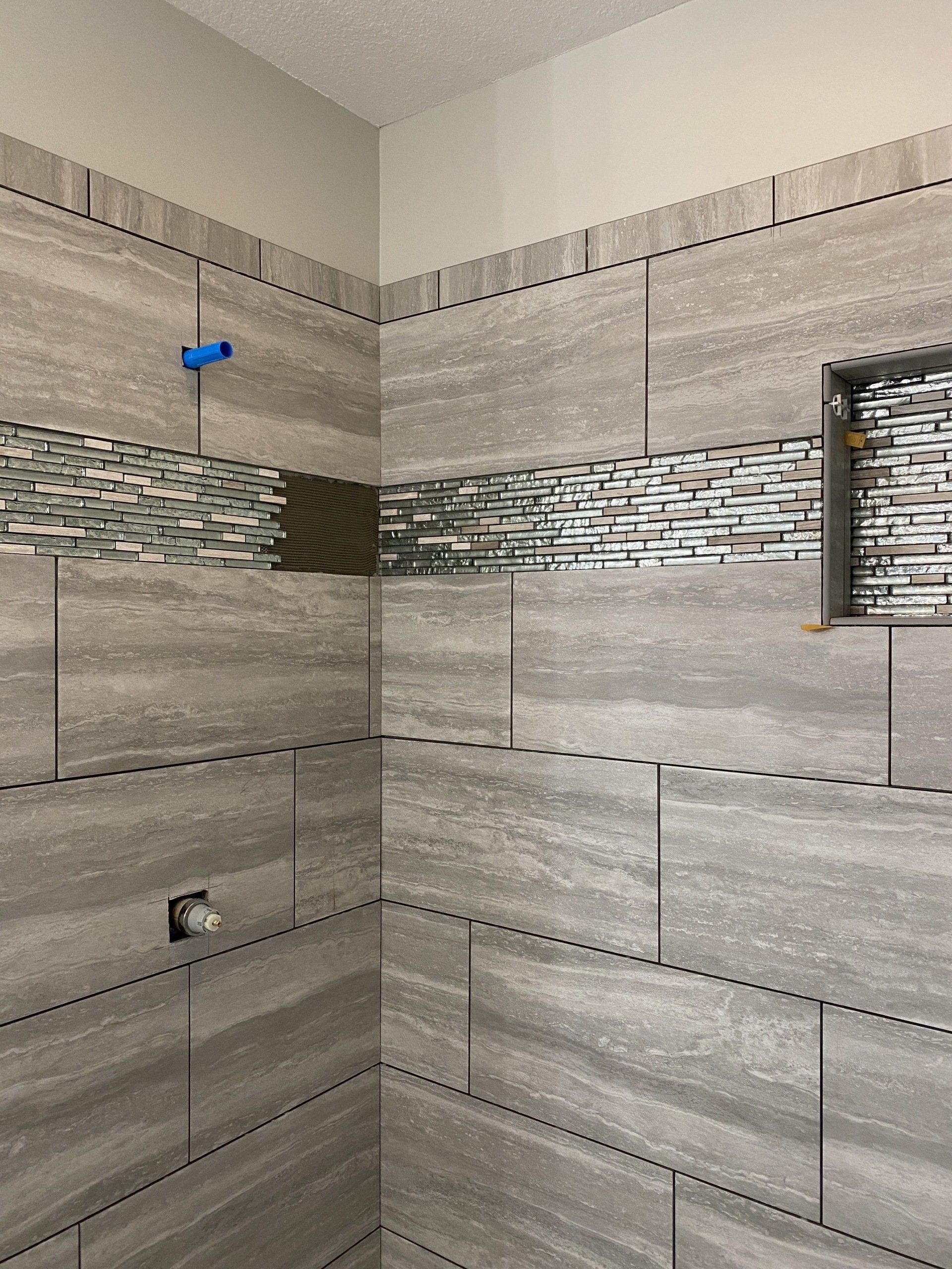 A bathroom with tiled walls and a shower stall.