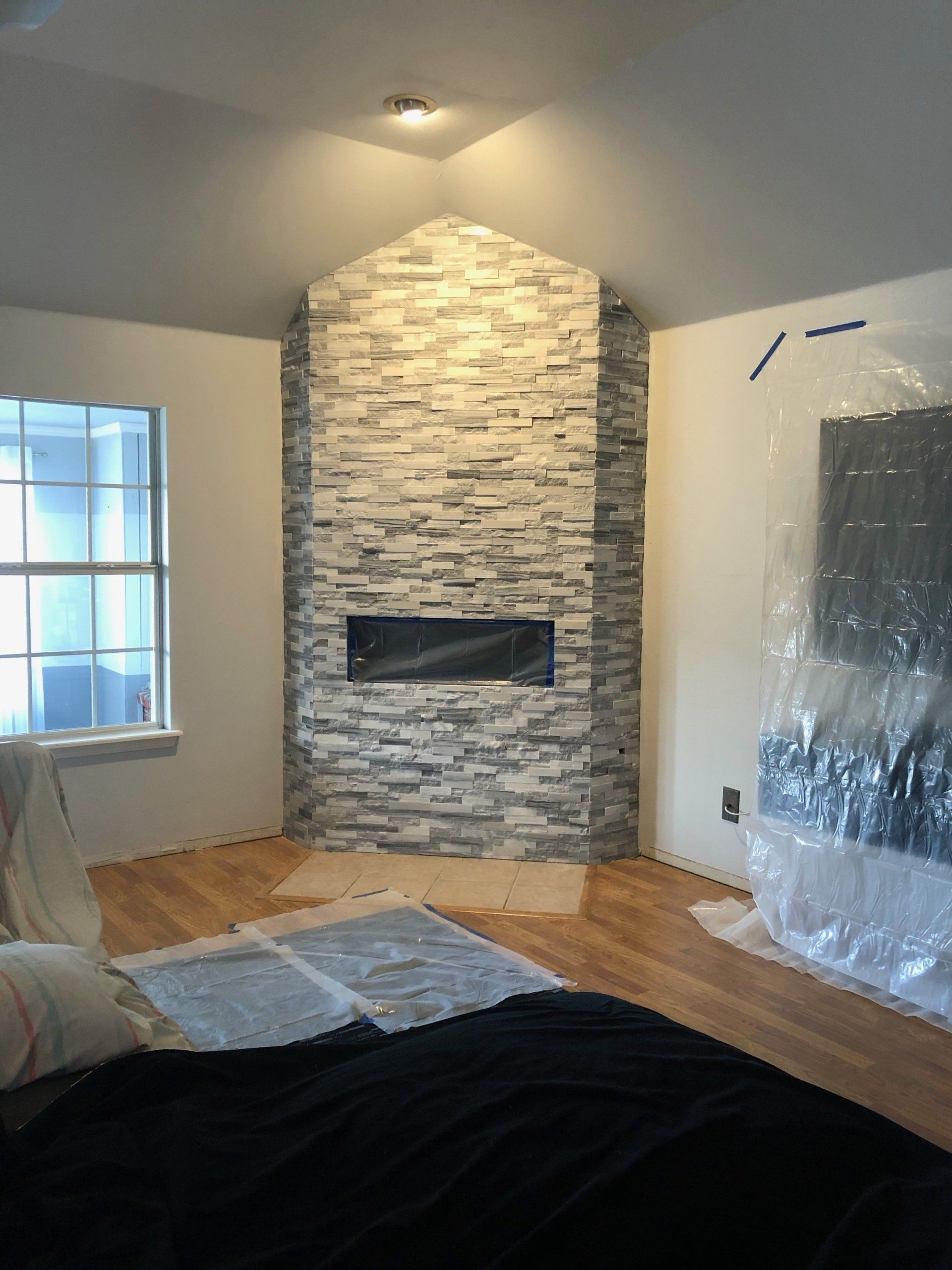 A living room with a stone fireplace and a flat screen tv.