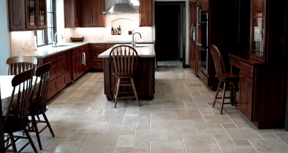 A kitchen with wooden cabinets , a large island , a table and chairs.