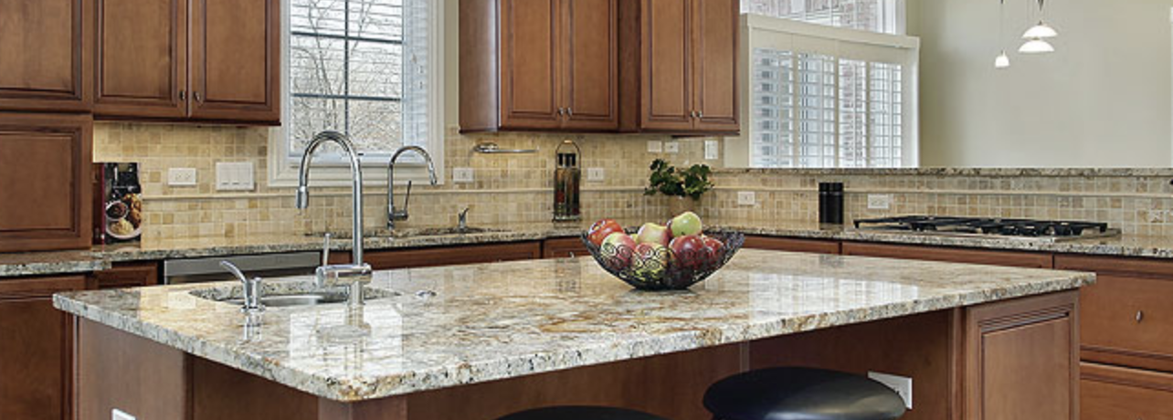 There is a bowl of fruit on the counter in the kitchen.