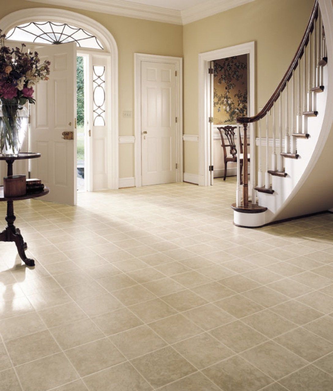 A hallway with a staircase and a table with flowers on it