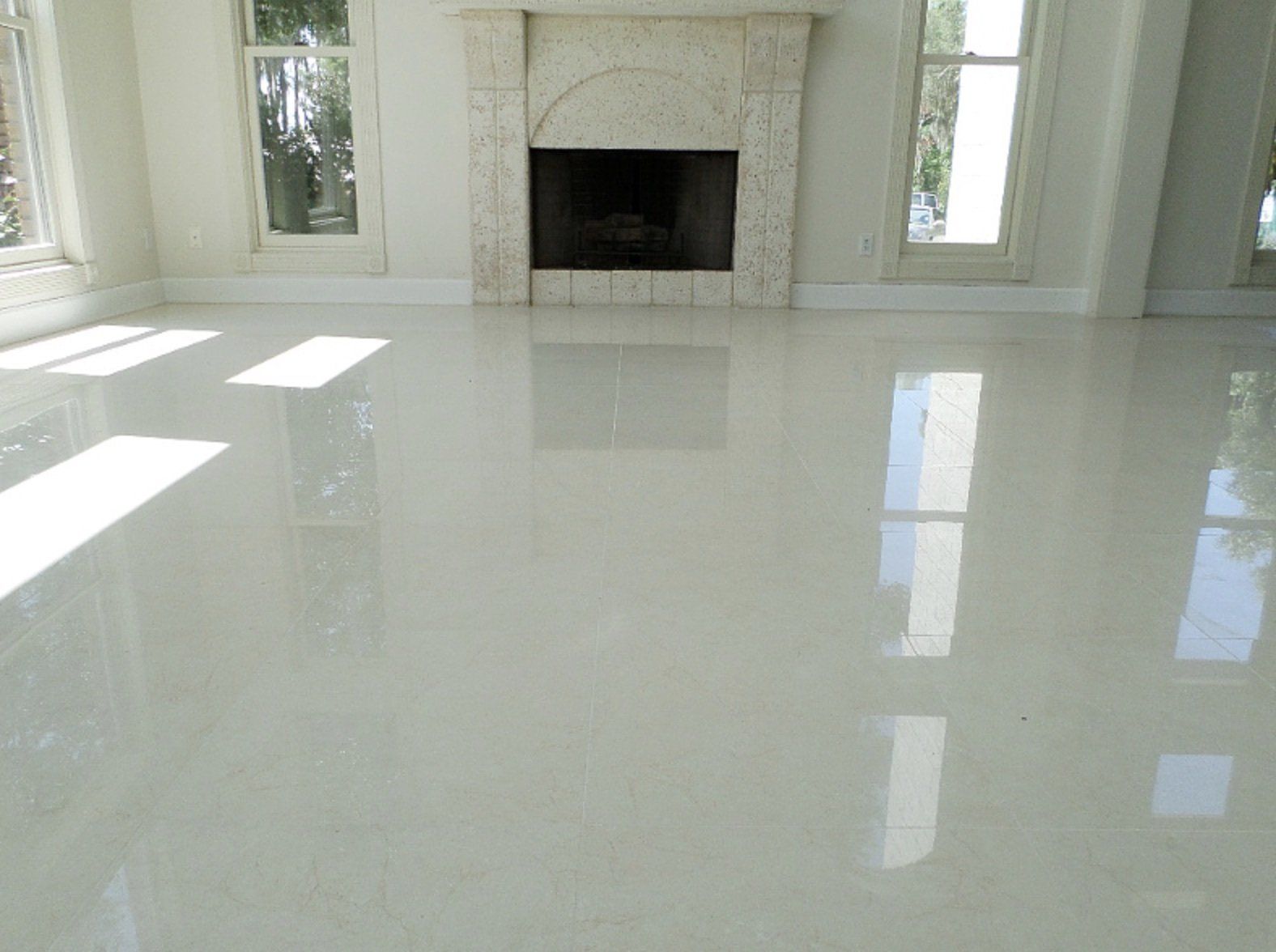 A living room with a fireplace and a shiny white floor.