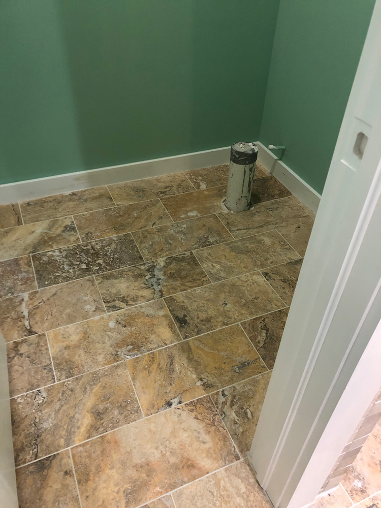 A bathroom with a tiled floor and green walls.