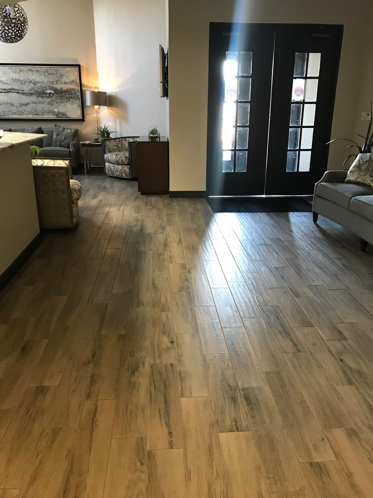 A living room with hardwood floors , a couch , chairs and a door.