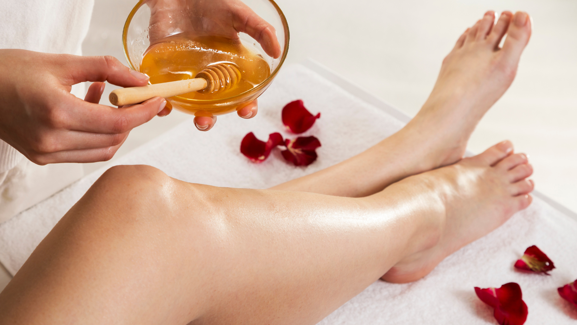 A woman is getting a honey treatment on her legs.