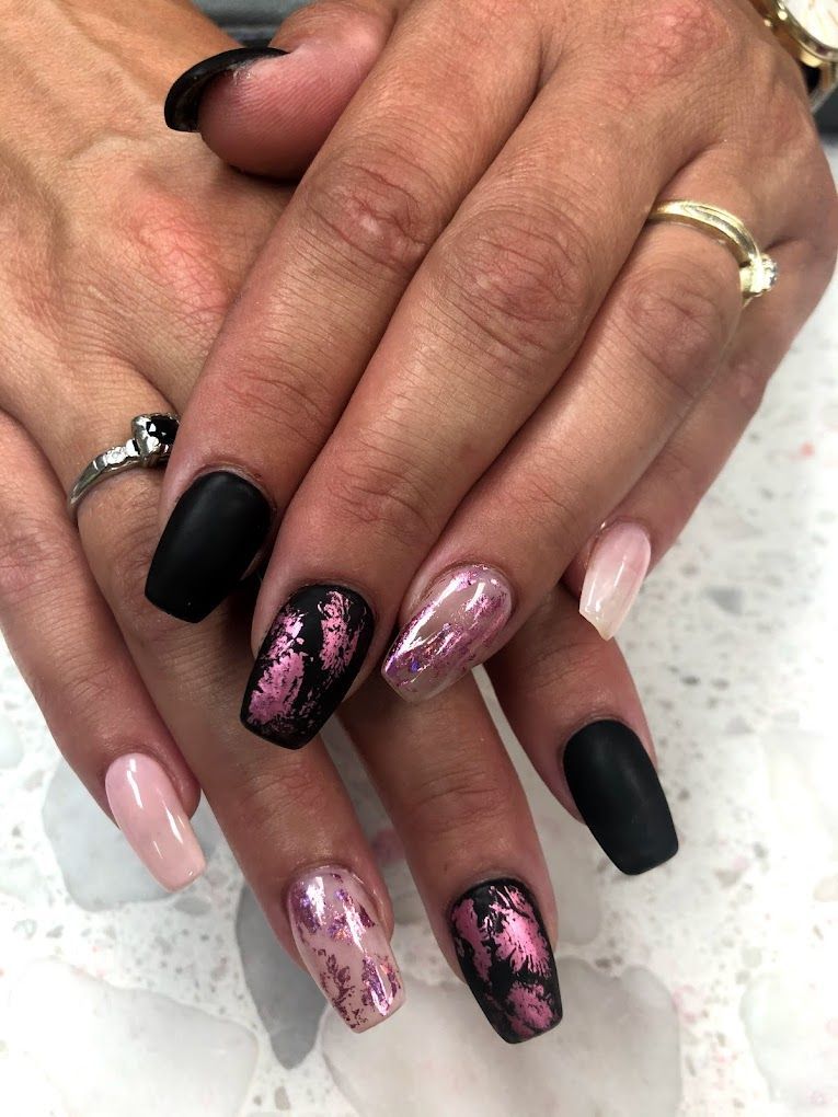 A close up of a woman 's hands with black and pink nails.