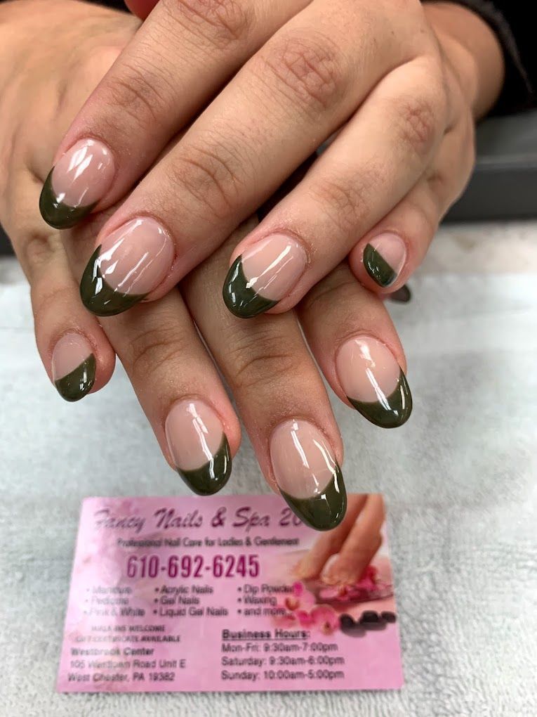 A close up of a woman 's nails with a green french manicure.