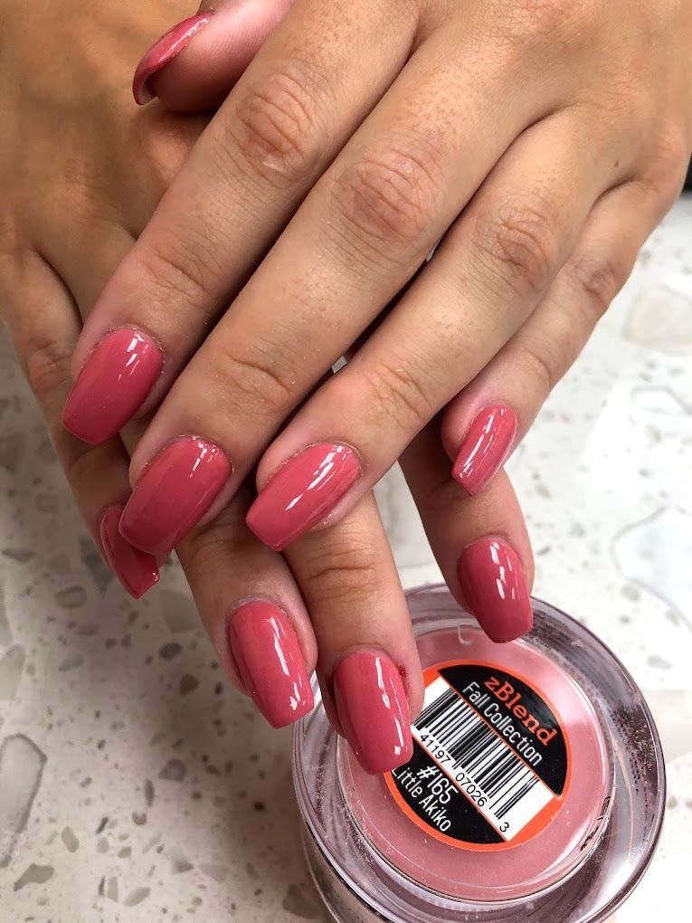A close up of a woman 's nails next to a jar of dip powder