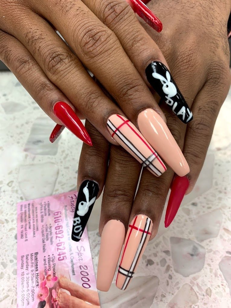 A close up of a woman 's nails with plaid and playboy bunny designs.