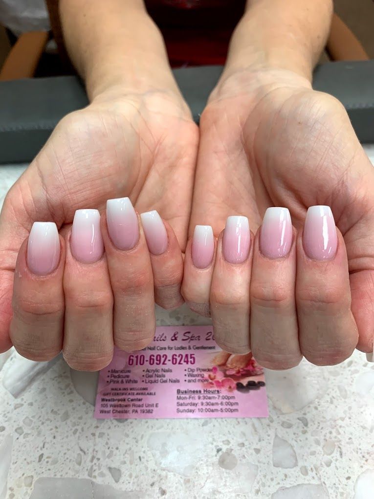 A woman 's hands with pink and white nails and a business card.