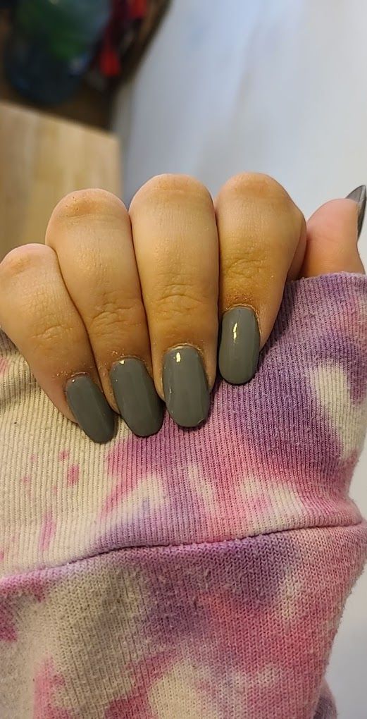 A close up of a person 's nails on a tie dye sweater.