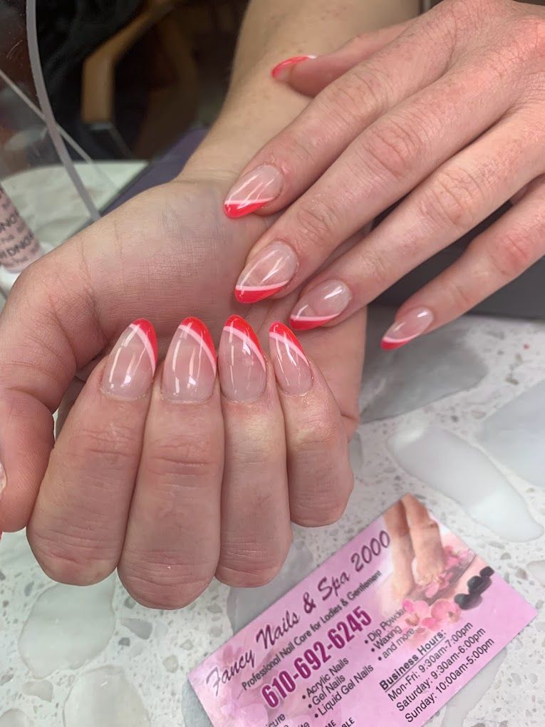 A close up of a woman 's nails with a red french manicure.